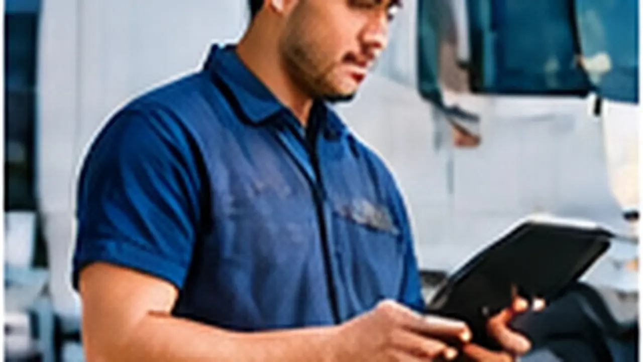 Self-employed tradie checking figures on a tablet beside his van