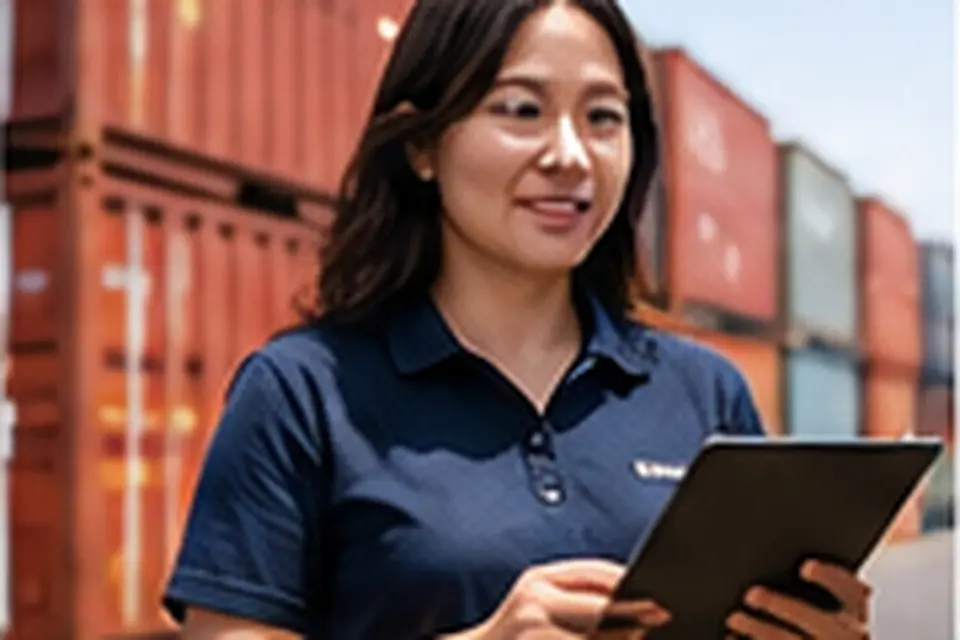 Importer checking a shipment on a tablet in front of shipping containers